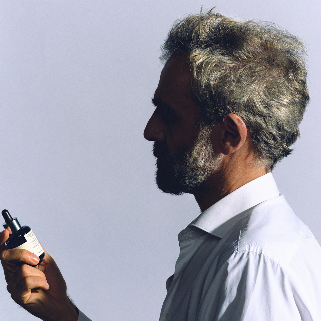 Homme tenant le sérum revitalisant fortifiant dans la main