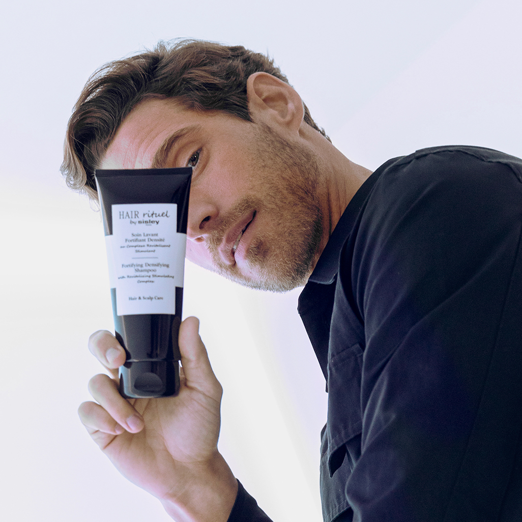 Homme tenant le shapoing fortifiant densité dans la main