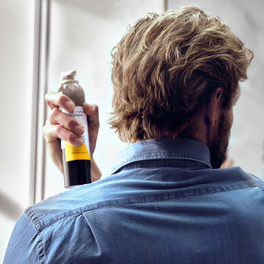 Homme applicant le spray fixant invisible sur ses cheveux