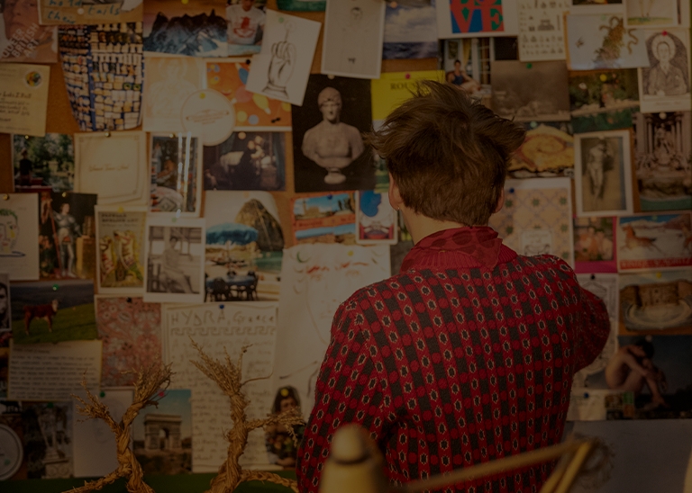 Luke Edward Hall from behind in front of his illustrations