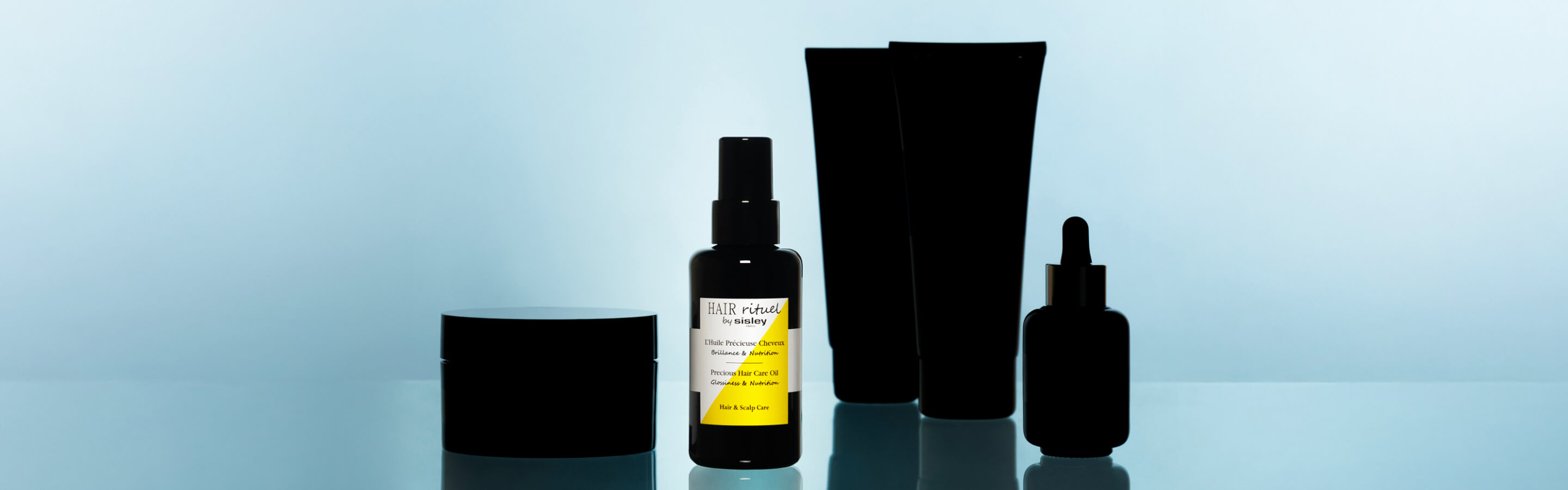 Der Precious Hair Care Oil Flakon im Rampenlicht, zusammen mit anderen Produkten aus der Hair Rituel Serie